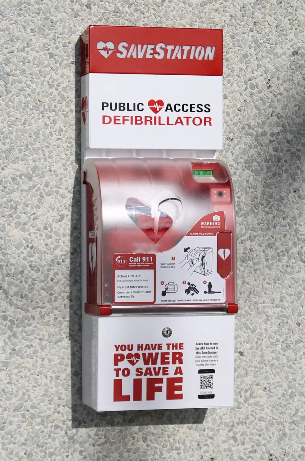 SaveStation public access defibrillator hung on a pebble wall.